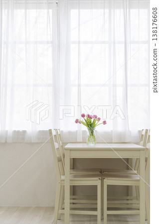 A dining table with a vase of pink tulips on it. A dining table with a vase of pink tulips on it. 138176608