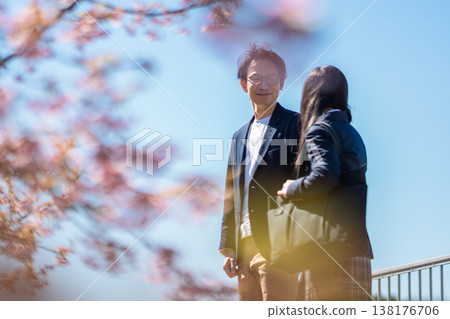櫻花樹下,老師面帶微笑,輕聲細語地與學生交談。 櫻花樹下,老師面帶微笑,輕聲細語地與學生交談。 138176706