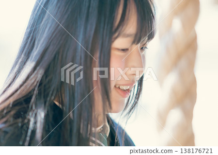 A high school girl in uniform quietly closes her eyes and clasps her hands together in prayer at a shrine. A high school girl in uniform quietly closes her eyes and clasps her hands together in prayer at a shrine. 138176721