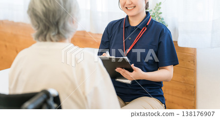 A female caregiver interviews a senior woman in a wheelchair. A female caregiver interviews a senior woman in a wheelchair. 138176907