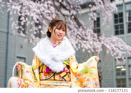 日本女性身著振袖和服,在櫻花樹下慶祝成年禮。 日本女性身著振袖和服,在櫻花樹下慶祝成年禮。 138177131