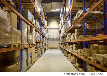 Warehouse aisle between high shelves stocked with boxes for inventory control Warehouse aisle between high shelves stocked with boxes for inventory control 138177206