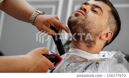 Man receives a haircut at a barber shop in the afternoon Man receives a haircut at a barber shop in the afternoon 138177672