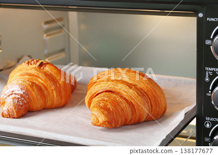 Fresh croissants baking in an oven during morning hours in a kitchen setting Fresh croissants baking in an oven during morning hours in a kitchen setting 138177677