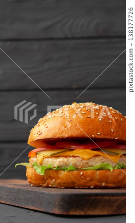 Burger with sesame seed bun on cutting board in kitchen setting during daylight Burger with sesame seed bun on cutting board in kitchen setting during daylight 138177726