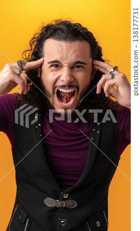 Man shows strong emotions with hands on head and mouth open in front of bright yellow background Man shows strong emotions with hands on head and mouth open in front of bright yellow background 138177731