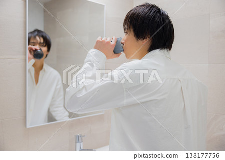 man brushing teeth in bathroom man brushing teeth in bathroom 138177756