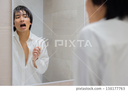 man brushing teeth in bathroom 138177763