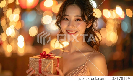 A young Japanese woman smiles shyly, holding a small gift. A young Japanese woman smiles shyly, holding a small gift. 138178199
