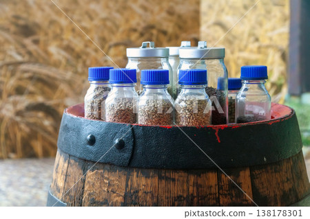 Beer ingredients in glass jars on wooden barrel 138178301