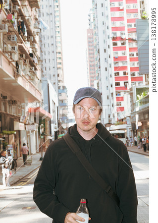 Caucasian Man Holding Bottle on Hong Kong City Street 138178995