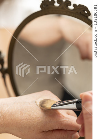 A woman's hands applying makeup. A woman's hands applying makeup. 138180591