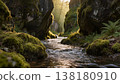 A river flows through a moss-covered canyon, sunlight filtering through narrow rock formations to create dynamic shadows on the water surface, maintaining shallow depth of field. 138180910