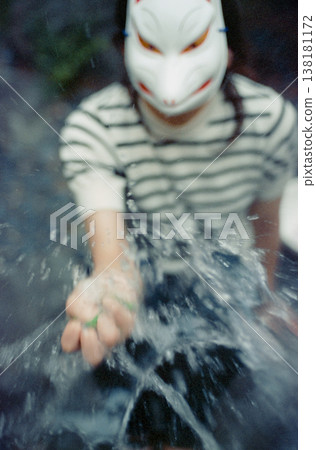 A person in a fox mask who makes water burst in their hands A person in a fox mask who makes water burst in their hands 138181172