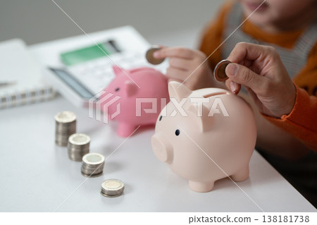 Child saving coins in piggy bank with parent Child saving coins in piggy bank with parent 138181738