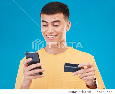 Credit card, ecommerce and man with a smartphone, payment and transaction on a blue background. Person, guy and happy model with a cellphone, digital app and online banking with finance and savings 138182357