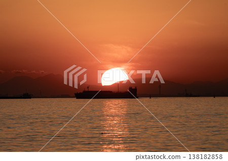夕陽西下，海面上映照著一艘船的輪廓，倒映在水面上。 138182858