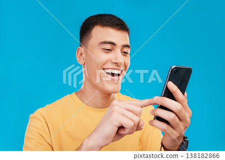 Phone, excited and young man in a studio scroll on social media, mobile app or the internet. Smile, happy and male person from Canada networking on website with cellphone isolated by blue background. 138182866