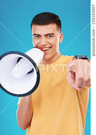 Megaphone, happy and portrait of man in studio pointing for announcement, speech or rally. Smile, protest and young person from Canada with bullhorn for loud communication isolated by blue background 138183007
