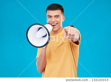 Bullhorn, happy and portrait of man in studio pointing for announcement, speech or rally. Smile, protest and young person from Canada with megaphone for loud communication isolated by blue background 138183014