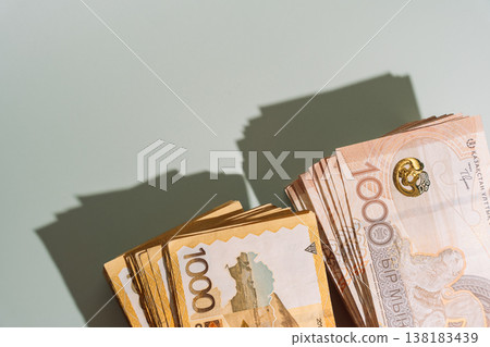 Stacks of 1000 Kazakhstani tenge banknotes with different designs on green background with hard shadow Stacks of 1000 Kazakhstani tenge banknotes with different designs on green background with hard shadow 138183439