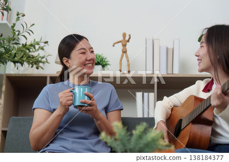 Mother enjoying a guitar performance by her daughter Mother enjoying a guitar performance by her daughter 138184377
