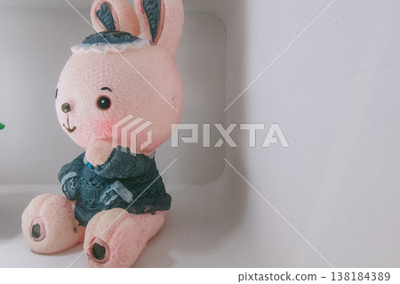 Cute Pink Bunny Figurine in Blue Hat and Sweater Isolated in Studio Cute Pink Bunny Figurine in Blue Hat and Sweater Isolated in Studio 138184389