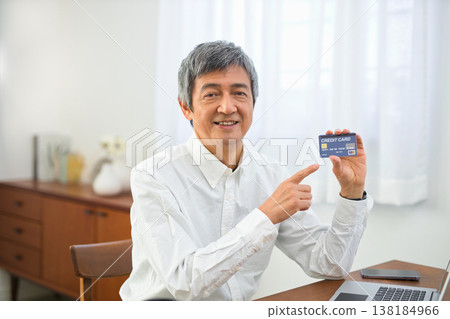 A man in his 60s looking at cards in the living room. A man in his 60s looking at cards in the living room. 138184966