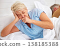 Couple, coughing or sick old woman in bed with husband or man with flu virus, tuberculosis or health problem. Chest pain, mature lady or senior person with cold, fever or lung illness in home bedroom 138185388