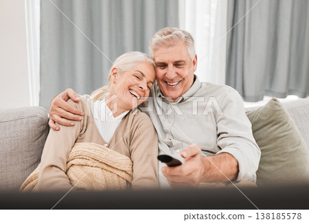 Senior couple, tv and laughing with love on a living room sofa with smile and movie at home. Elderly people, bonding and marriage in retirement with series and streaming in lounge on a couch together 138185578