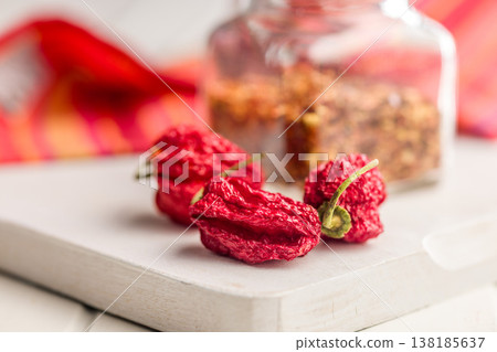 Dried Ghost Chili Peppers and Jar of Crushed Chili Flakes on White Table for Spicy Cooking 138185637