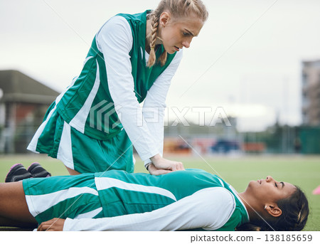 First aid, cpr and accident with a hockey player on a field to save a player on her team during an emergency. Fitness, sports and heart attack with a woman helping her friend on a field of grass 138185659