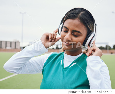 Athlete, sports or woman in headphones for music or streaming radio playlist on a hockey turf. Relax, break or zen Indian girl player listening to calm audio, sound or fitness podcast for inspiration 138185688