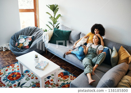 Lesbian couple, relax and watching tv on couch, hug and comfort in home or living room, bonding and chilling. Happy cozy people, streaming a series or movie with remote for quality time, love and joy 138185800