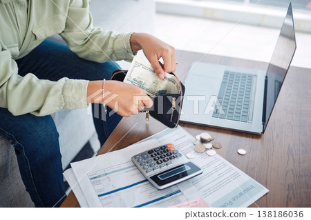 Hands, wallet and cash, budget or bills, money management with laptop and calculator for tax paperwork. Financial plan, person with info on insurance policy documents, audit and loan payment at home Hands, wallet and cash, budget or bills, money management with laptop and calculator for tax paperwork. Financial plan, person with info on insurance policy documents, audit and loan payment at home 138186036