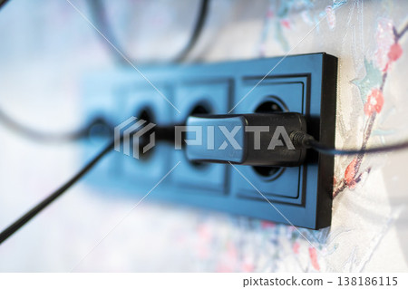 Plug linked to power strip indoors. Cord and plug setup with fabric background in room Plug linked to power strip indoors. Cord and plug setup with fabric background in room 138186115