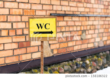 Dusty outdoor restroom indicator attached to brick wall in wintery city environment Dusty outdoor restroom indicator attached to brick wall in wintery city environment 138186322