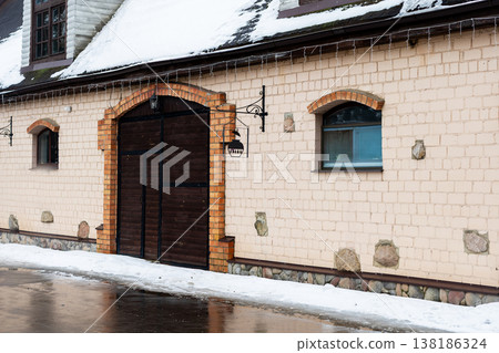 Snowcovered brick with lantern reflections. Historic arched doorway amidst snow and wet pavement Snowcovered brick with lantern reflections. Historic arched doorway amidst snow and wet pavement 138186324