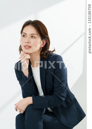 Portrait of a middle-aged woman wearing a navy jacket against a white background (vertical orientation). Portrait of a middle-aged woman wearing a navy jacket against a white background (vertical orientation). 138186709