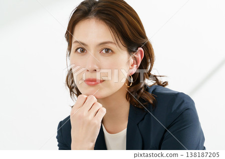 A portrait of a middle-aged woman wearing a navy jacket against a white background. A portrait of a middle-aged woman wearing a navy jacket against a white background. 138187205