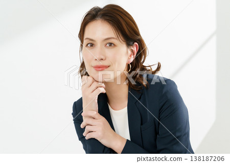A portrait of a middle-aged woman wearing a navy jacket against a white background. A portrait of a middle-aged woman wearing a navy jacket against a white background. 138187206
