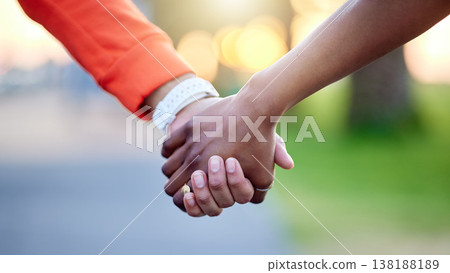 Interracial couple, holding hands and love in nature for support, trust or unity together. Closeup of people touching in romance, care or friendship walk in an outdoor park for partnership or duo Interracial couple, holding hands and love in nature for support, trust or unity together. Closeup of people touching in romance, care or friendship walk in an outdoor park for partnership or duo 138188189