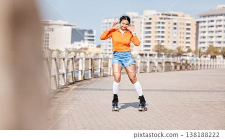 Girl, rollerskates and smile with headphones, boardwalk and fun by ocean, sea and outdoors for hobby. Active person, skating and sport in summer, music and gear for safety, energy and happy in summer Girl, rollerskates and smile with headphones, boardwalk and fun by ocean, sea and outdoors for hobby. Active person, skating and sport in summer, music and gear for safety, energy and happy in summer 138188222