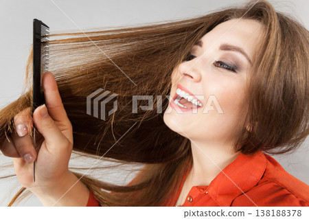 Woman combing her brown hair Woman combing her brown hair 138188378