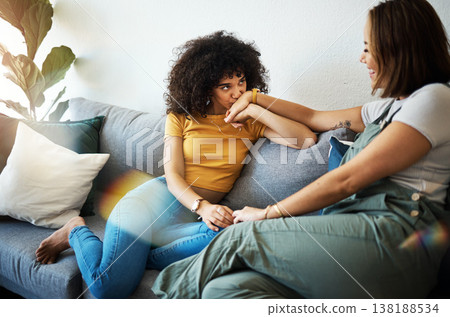 Conversation, love and lesbian couple bonding on a sofa in the living room talking and relaxing. Happy, communication and young interracial lgbtq women speaking and resting together in lounge at home 138188534