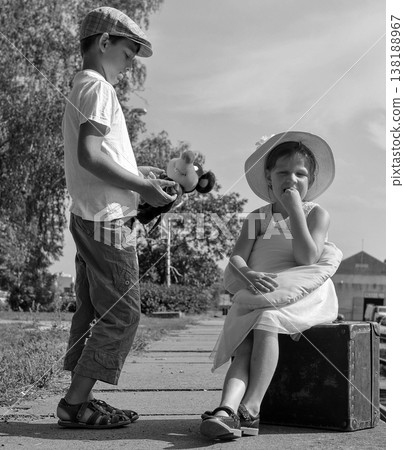Brother offers toy to sister sitting on suitcase, waiting for journey Brother offers toy to sister sitting on suitcase, waiting for journey 138188967