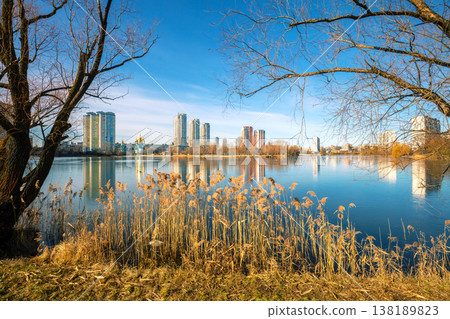 Skyline, Kyiv city in the morning. Left bank of the Dnieper River. Lakeshore with trees in the morning. Beautiful reflection of buildings in the lake 138189823