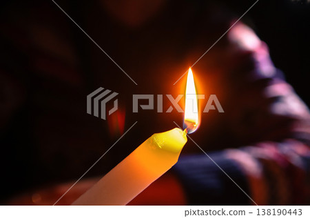 Close-up of a burning candle in the dark. Single candle flame glowing against a black background. Concept of hope, memory, spirituality, or mourning Close-up of a burning candle in the dark. Single candle flame glowing against a black background. Concept of hope, memory, spirituality, or mourning 138190443