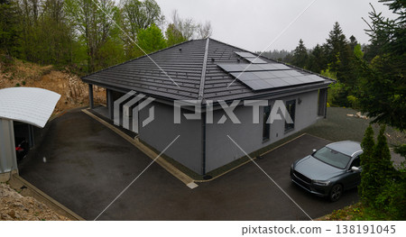 Modular modern smart house with solar panels and car in forested driveway during overcast day Modular modern smart house with solar panels and car in forested driveway during overcast day 138191045