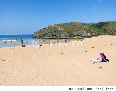 Couple Relaxing On Sandy Beach Near Rocky Headland With Swimmers And Clear Blue Sea On A Sunny Summer Day Couple Relaxing On Sandy Beach Near Rocky Headland With Swimmers And Clear Blue Sea On A Sunny Summer Day 138191656
